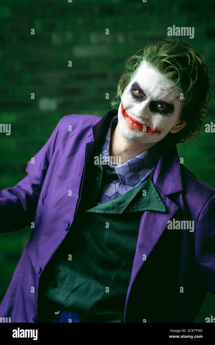 Ritratto di un giovane cosplayer maschile vestito da Joker e divertiti mentre sorridi e guarda direttamente la fotocamera con spazio di copia Foto Stock