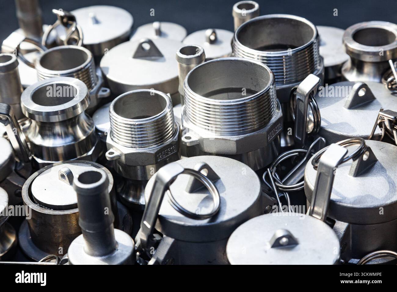 Boccole, raccordi, raccordi filettati e nippli nuovi in acciaio inox. Primo piano di una pila di raccordi in acciaio. Foto Stock