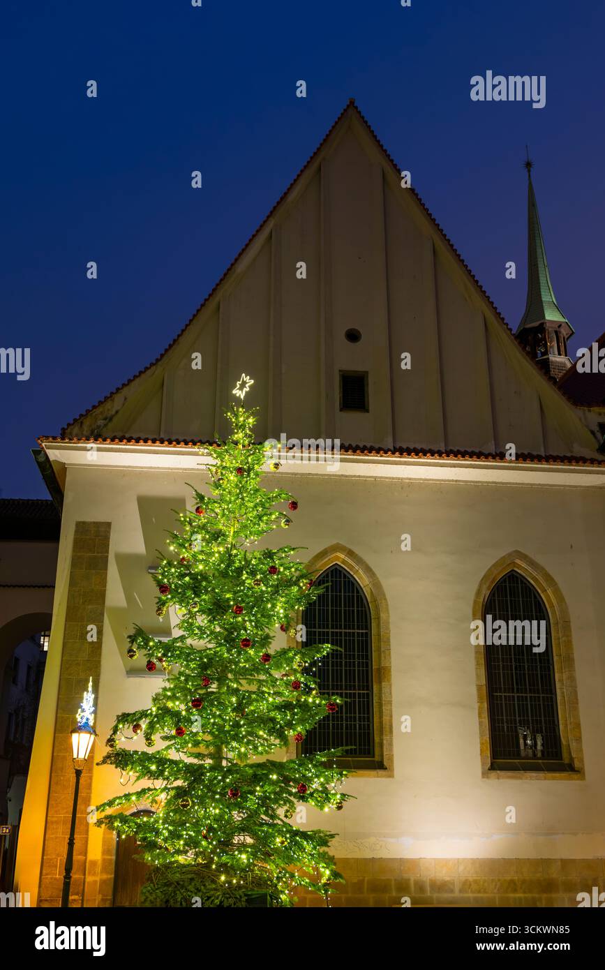 Albero di Natale decorato in piedi di fronte alla Cappella di Betlemme a Praga, Cechia, durante l'ora blu Foto Stock