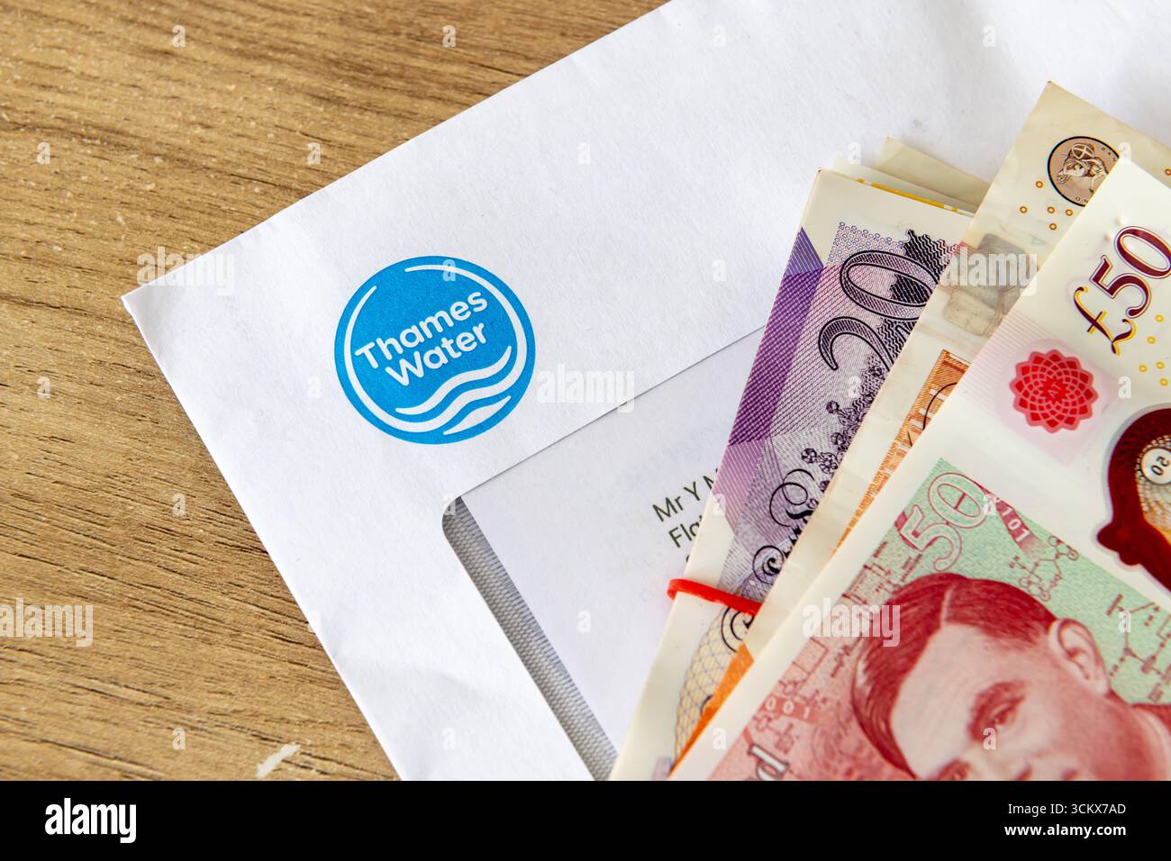 Londra. Regno Unito - 31 agosto 2025. Un primo piano macro di una bolletta dell'acqua del Tamigi con una pila di banconote in sterline in cima. Foto Stock
