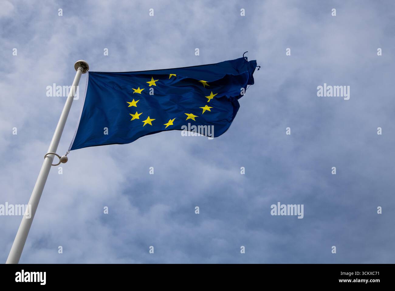 Bandiera dell'Unione europea che fluttua nel vento, blu con stelle dorate, posta contro un cielo naturale luminoso, simboleggia l'Europa, l'unità e l'identità Foto Stock