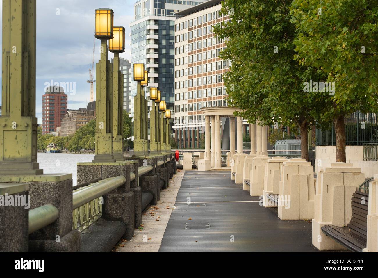 Una passerella lungo il fiume Tamigi a Londra, caratterizzata da caratteristici lampioni. MI6 sul Tamigi, Londra Foto Stock