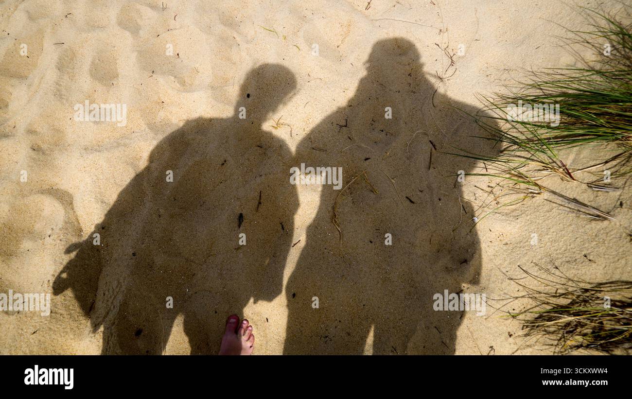 Ombra di due persone sulla sabbia alla luce del sole Foto Stock