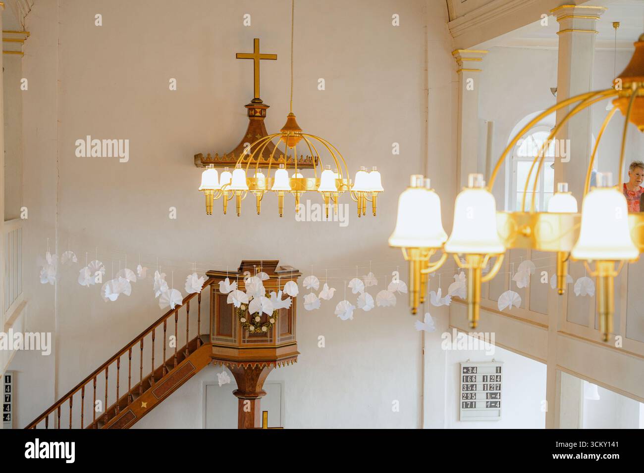 Gli interni della chiesa presentano lampadari decorati e delicate decorazioni di carta appese al balcone. Un'atmosfera serena riempie lo spazio, mostrando Foto Stock