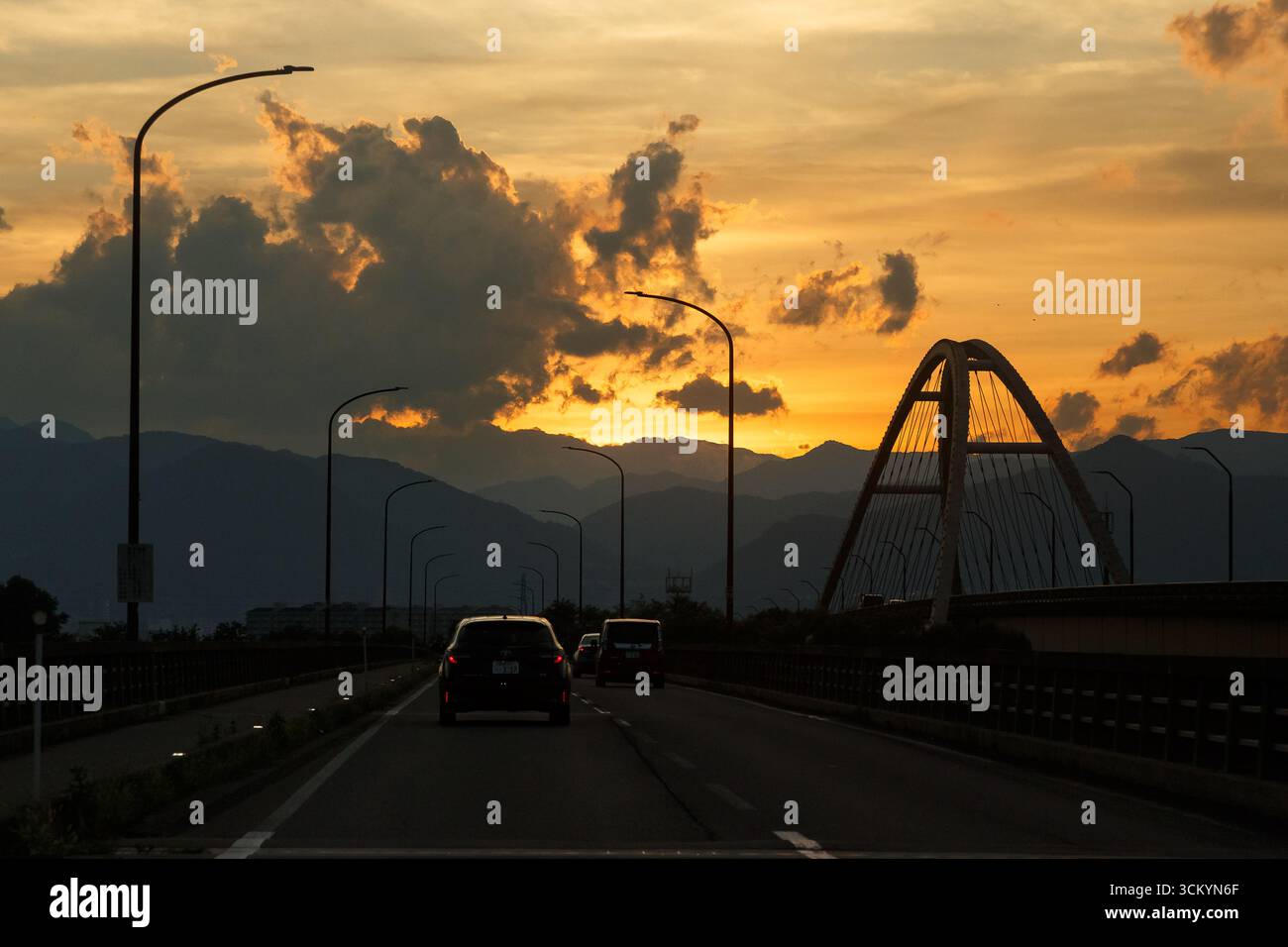 Auto e un ponte su una strada vicino a Nagano al tramonto. Nagano, Giappone. Foto Stock