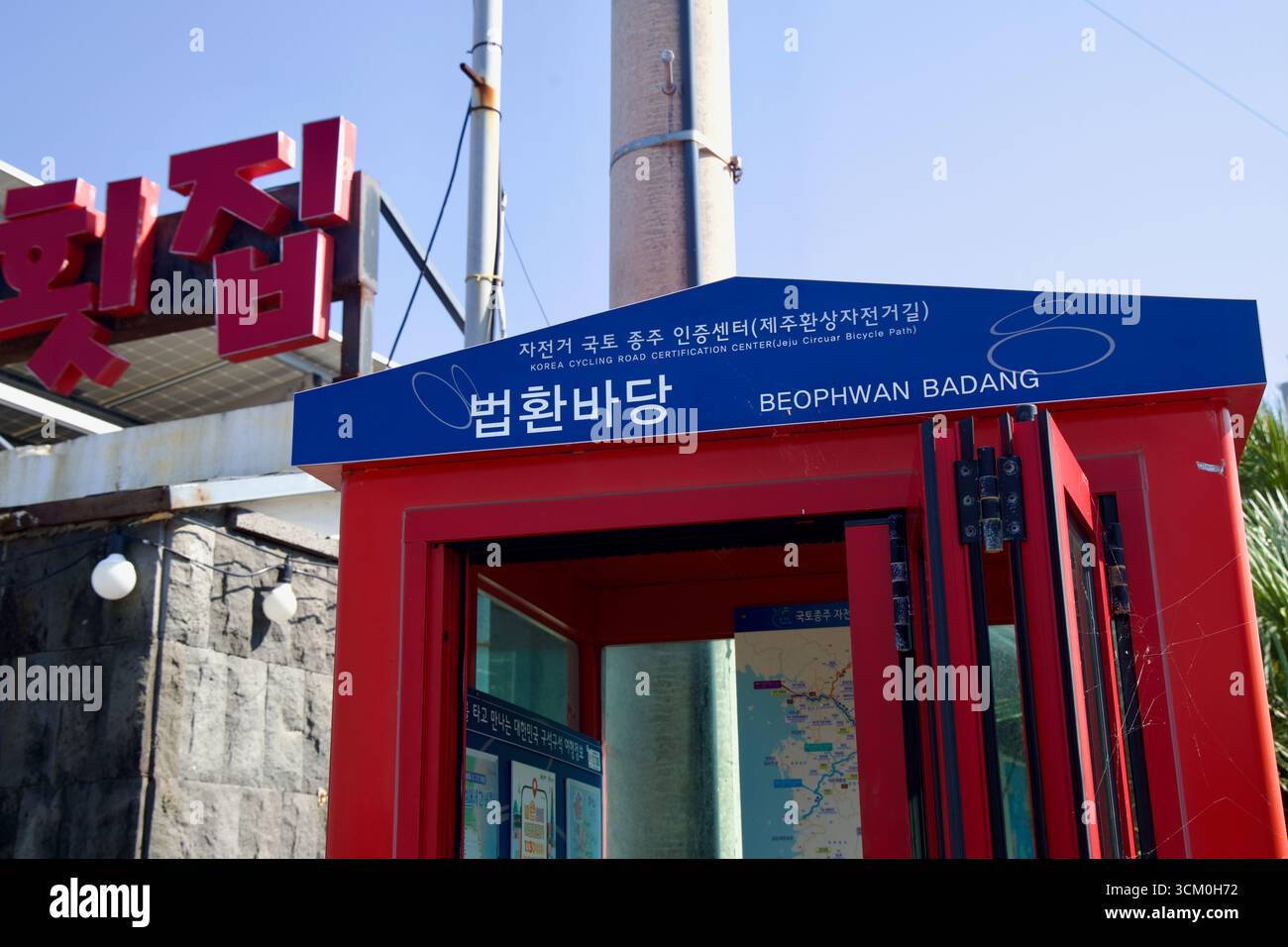Una vista ravvicinata del cartello del centro di certificazione Beophwan Badang sopra lo stand rosso, con scritte coreane e inglesi che segnano la Jeju Fantasy Bike Pat Foto Stock