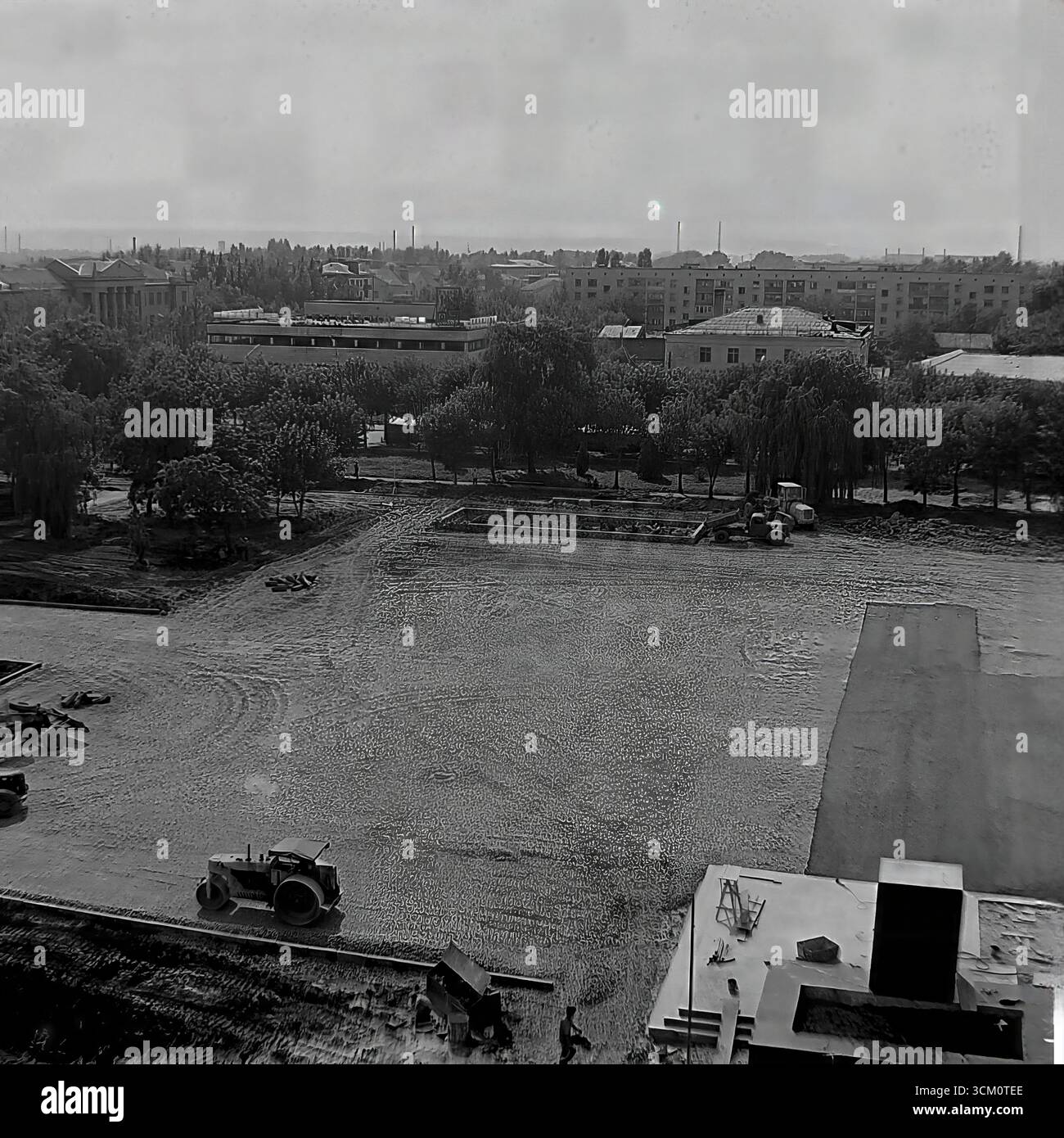 Una ricostruzione su larga scala della piazza centrale della Rivoluzione d'ottobre a Sloviansk, 1975-1976, alla vigilia del 300° anniversario della città. La foto cattura macchinari pesanti al lavoro, tra cui bulldozer e rulli stradali, durante il massiccio progetto di rinnovamento urbano e la costruzione del piedistallo per un nuovo monumento a Lenin. Questa fotografia è un potente documento di pianificazione urbana sovietica e un simbolo della vita creativa e pacifica nel Donbas, dove la città veniva trasformata per il suo grande giubileo Foto Stock