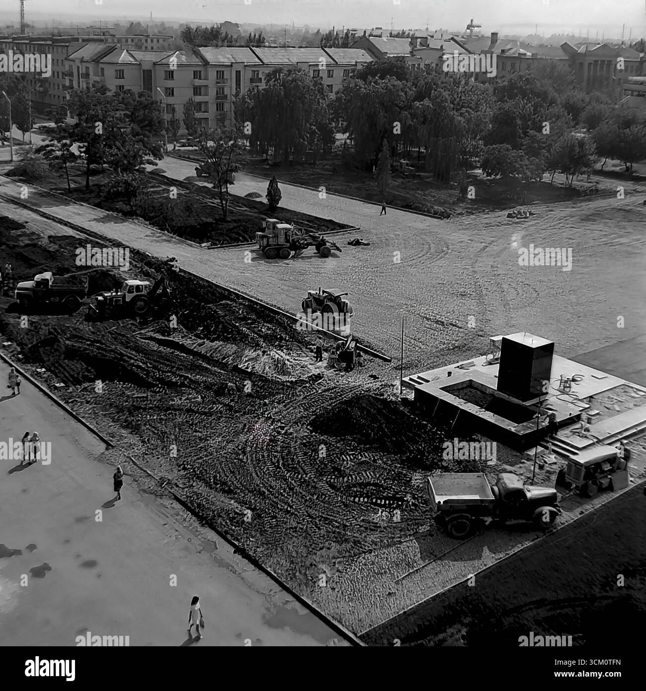Una ricostruzione su larga scala della piazza centrale della Rivoluzione d'ottobre a Sloviansk, 1975-1976, alla vigilia del 300° anniversario della città. La foto cattura macchinari pesanti al lavoro, tra cui bulldozer e rulli stradali, durante il massiccio progetto di rinnovamento urbano e la costruzione del piedistallo per un nuovo monumento a Lenin. Questa fotografia è un potente documento di pianificazione urbana sovietica e un simbolo della vita creativa e pacifica nel Donbas, dove la città veniva trasformata per il suo grande giubileo Foto Stock