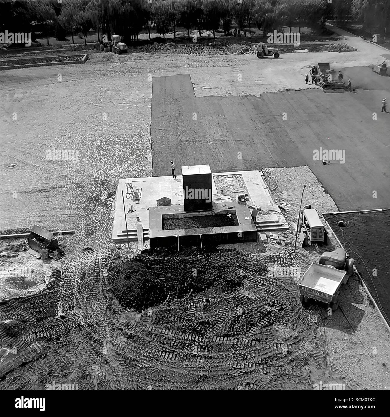 Una ricostruzione su larga scala della piazza centrale della Rivoluzione d'ottobre a Sloviansk, 1975-1976, alla vigilia del 300° anniversario della città. La foto cattura macchinari pesanti al lavoro, tra cui bulldozer e rulli stradali, durante il massiccio progetto di rinnovamento urbano e la costruzione del piedistallo per un nuovo monumento a Lenin. Questa fotografia è un potente documento di pianificazione urbana sovietica e un simbolo della vita creativa e pacifica nel Donbas, dove la città veniva trasformata per il suo grande giubileo Foto Stock