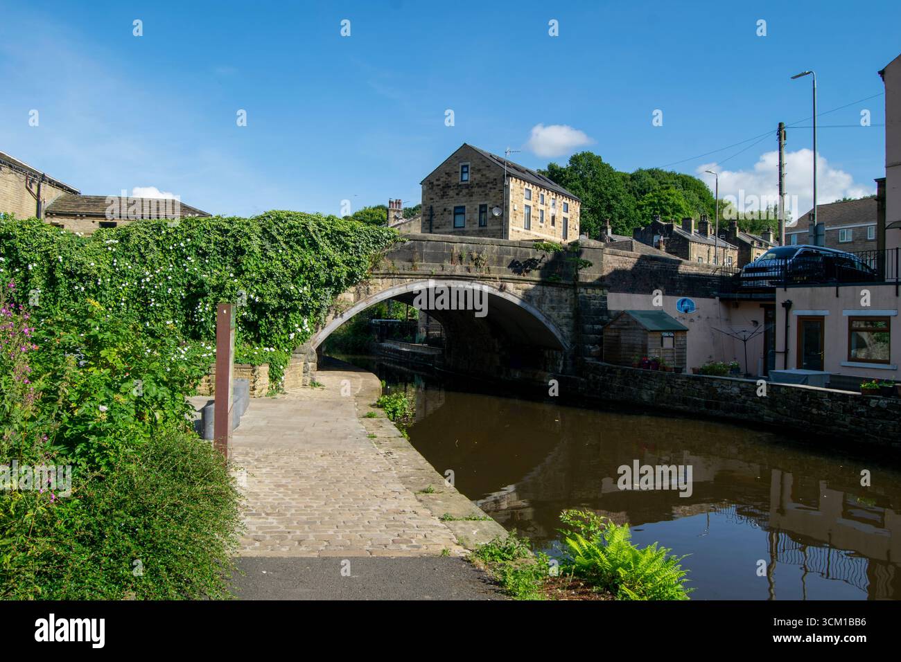 Rochdale Canal a Luddendenfoot, West Yorkshire, Inghilterra. Ponti storici e edifici sul canale in una giornata di sole, che mostrano la vita urbana dei canali. Foto Stock