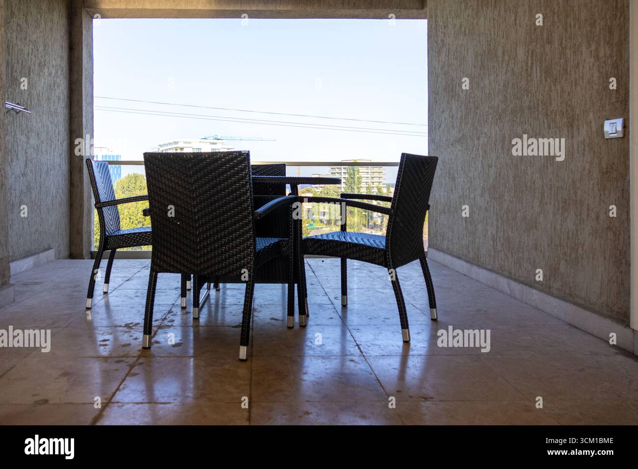 Area salotto con balcone con tavolo rotondo e sedie che offrono una vista dei moderni edifici della città Foto Stock