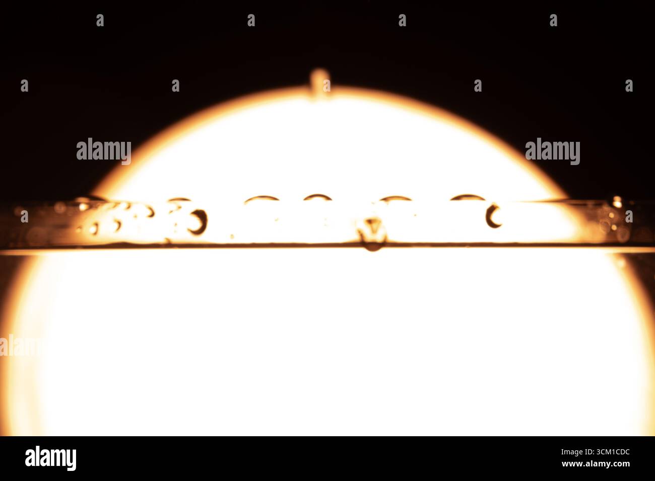 330.primo piano del tubo trasparente con gocce d'acqua allineate. La luce circolare sullo sfondo crea un alone luminoso. Riflessi e ombre migliorano i Foto Stock