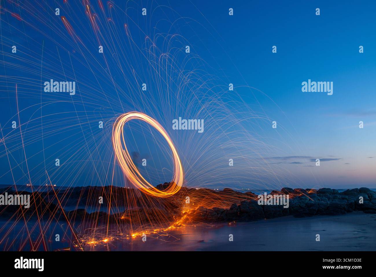 Fotografia di lana d'acciaio sotto un cielo blu subito dopo il tramonto sulla spiaggia, creando luci e riflessi spettacolari. Foto Stock