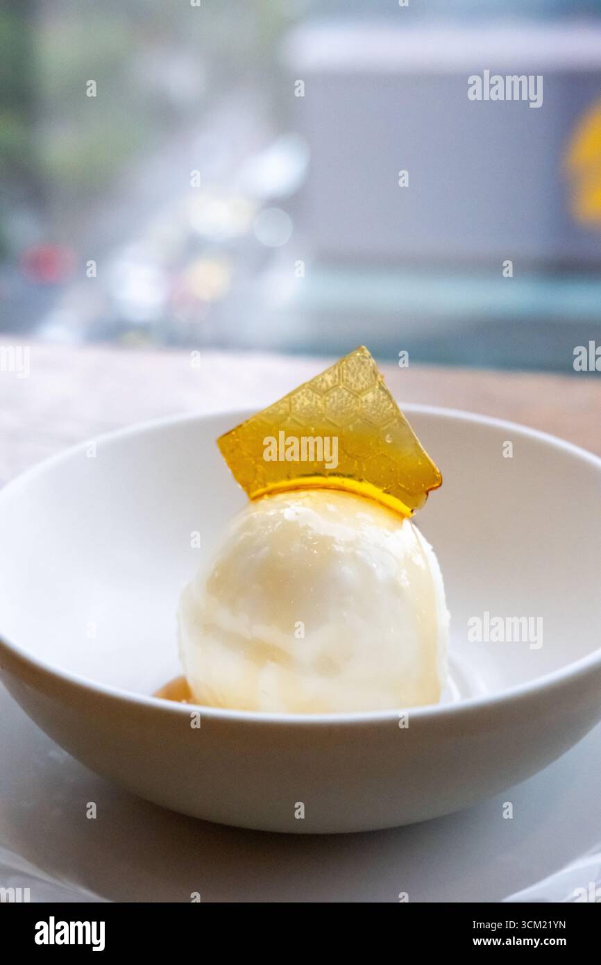 Gelato al miele con condimento, servito in una ciotola bianca Foto Stock