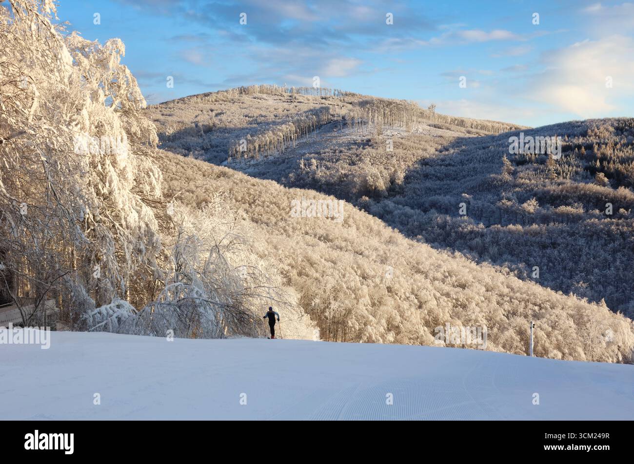 Nevicata appena preparata sulla pista da sci della stazione sciistica in una soleggiata giornata invernale Foto Stock