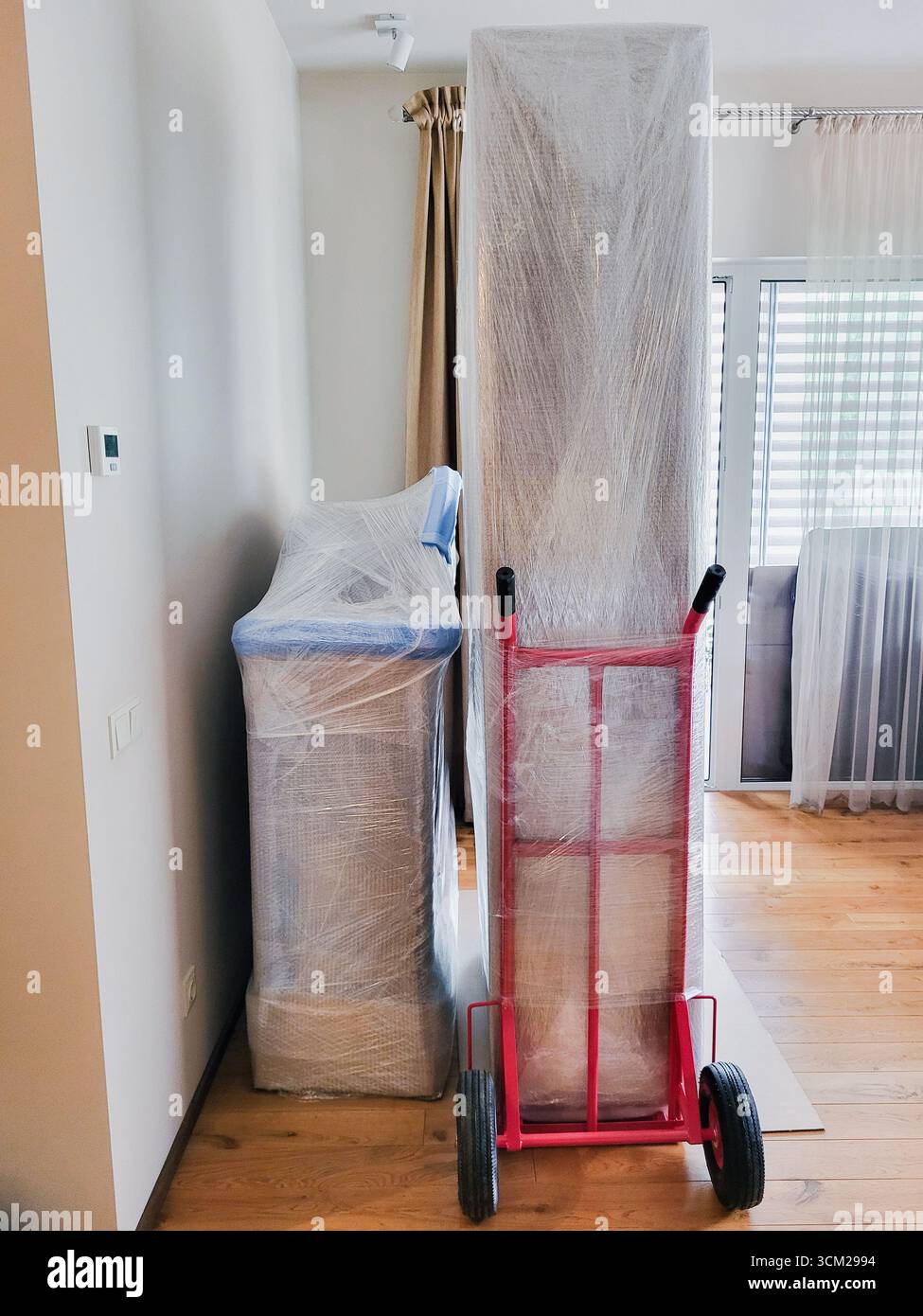 Mobili pronti per una nuova casa. Giorno in movimento: Armadietto avvolto pronto per il trasporto su camion a mano Foto Stock