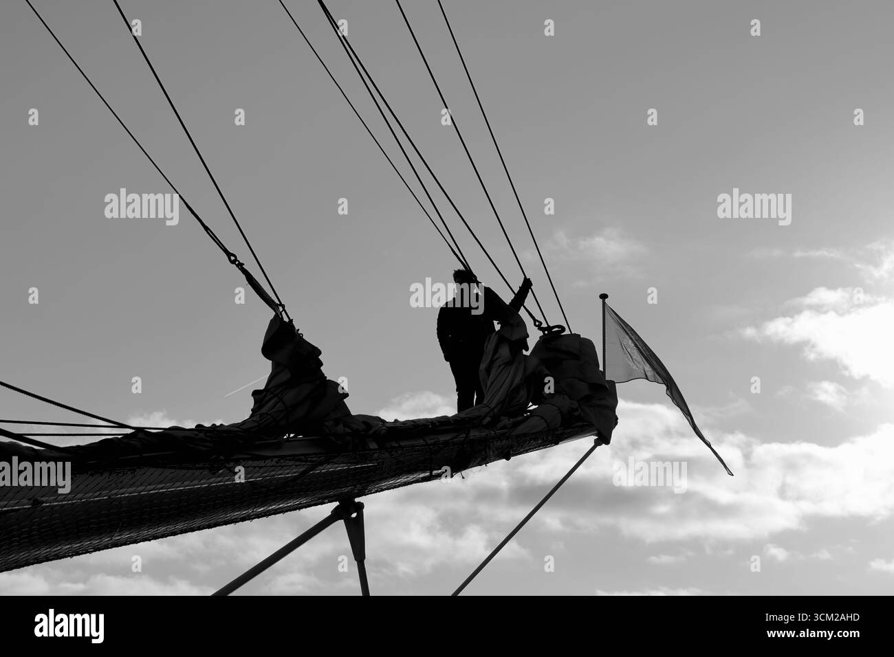 Linee di lavoro della silhouette dell'equipaggio su un velivolo a vela 2025 ad Amsterdam, Paesi Bassi, cielo retroilluminato con sartiame e vele con pelo chiaramente mostrate. Foto Stock