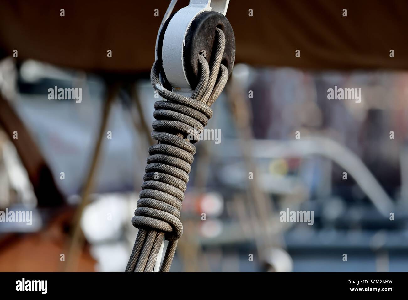 Vista ravvicinata di una fune a spirale su un blocco di legno a bordo di una nave a vela, fotografata durante la Sail 2025 ad Amsterdam, Paesi Bassi, dettagli di allestimento. Foto Stock