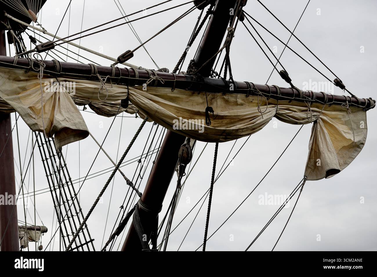 Naviga su tela di legno lungo un cortile con sartiame e blocchi su un veliero a Sail 2025, Amsterdam, Paesi Bassi, visto contro un cielo grigio e coperto. Foto Stock