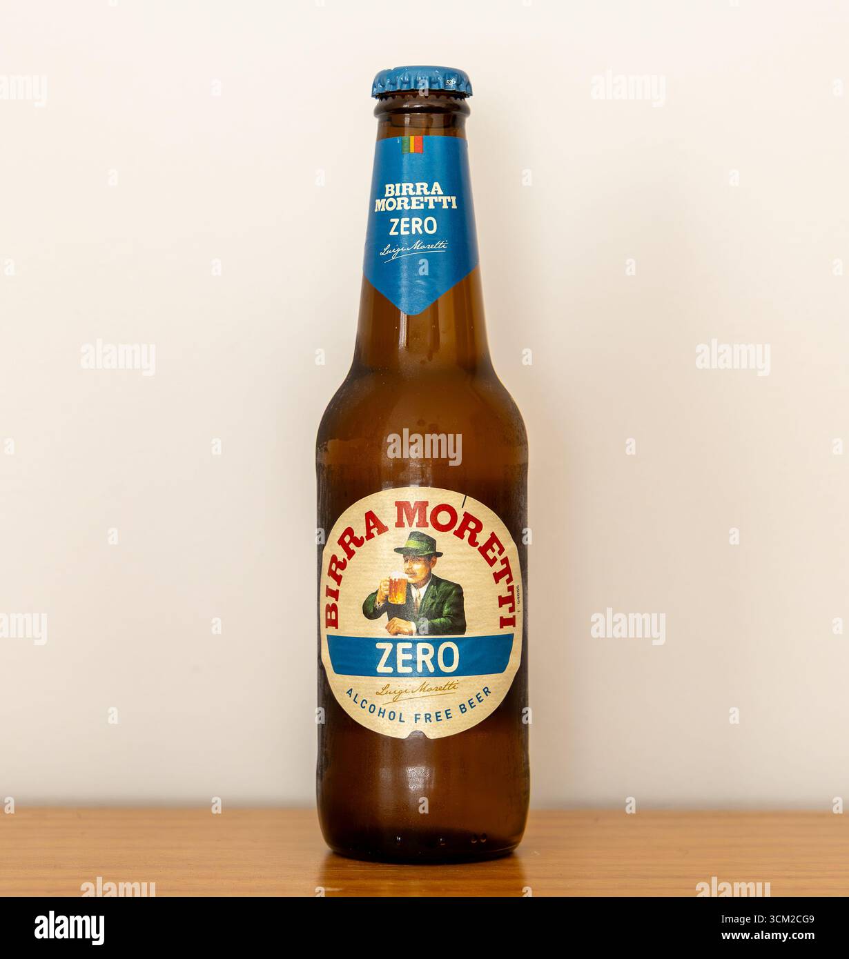 Una bottiglia di birra Moretti Zero senza alcool in piedi su una superficie di legno su un fondo pianeggiante Foto Stock