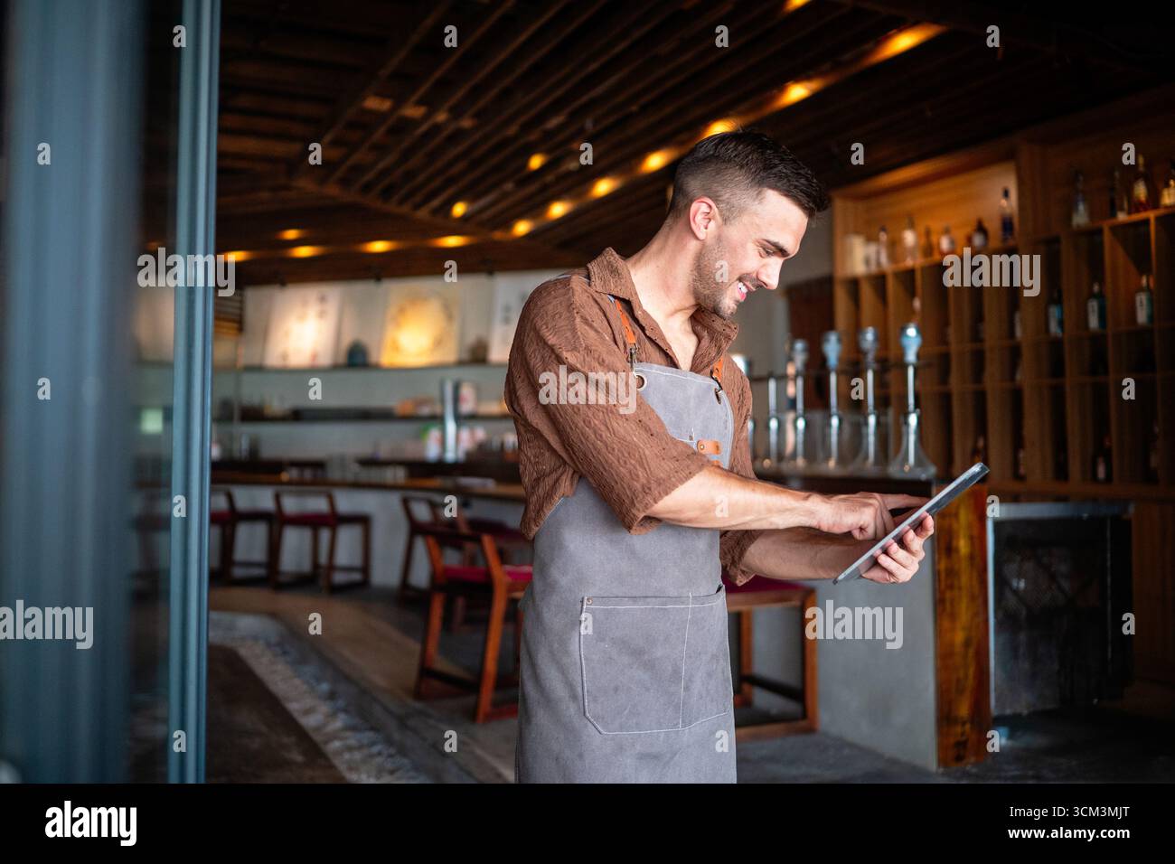 Barista appassionato e imprenditore che porta calore e servizio di qualità nella sua elegante caffetteria Foto Stock