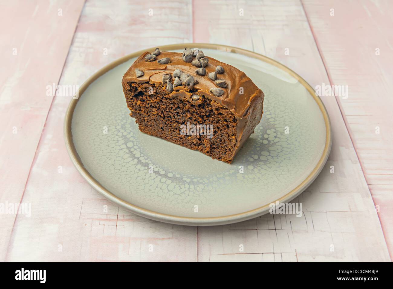 Deliziosa torta in spugna al cioccolato fondente con un morbido centro di fusione, ricoperta di ganache cremose e decorata con lamponi freschi Foto Stock