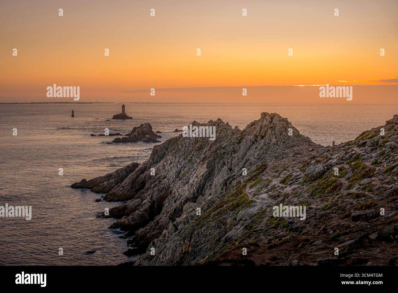 Tramonto a Pointe du Raz con il faro di la Vieille in lontananza, Bretagna Francia. West Point (Francia continentale), Atlantic, Cap Sizun, Golden Hour Foto Stock