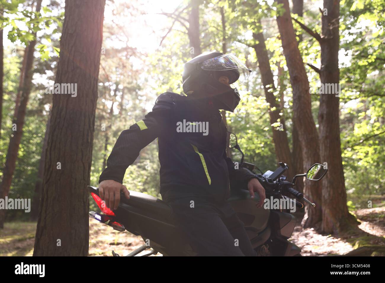 Giovane con casco e motocicletta moderna all'aperto Foto Stock