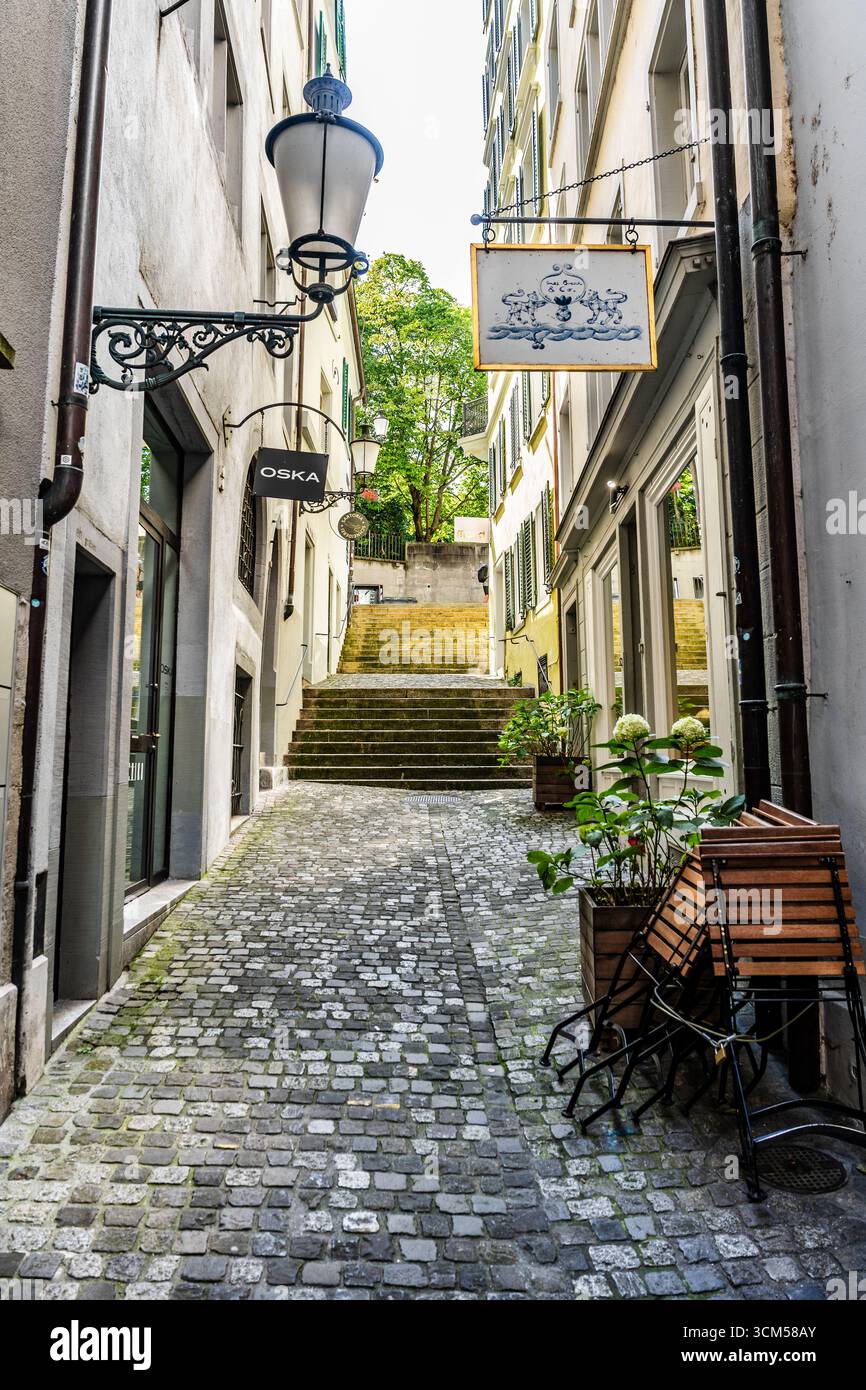 Weggengasse, vicolo stretto e pittoresco con piante, negozi e lanterne, strada tranquilla con fascino storico nella città vecchia di Zurigo, Svizzera Foto Stock