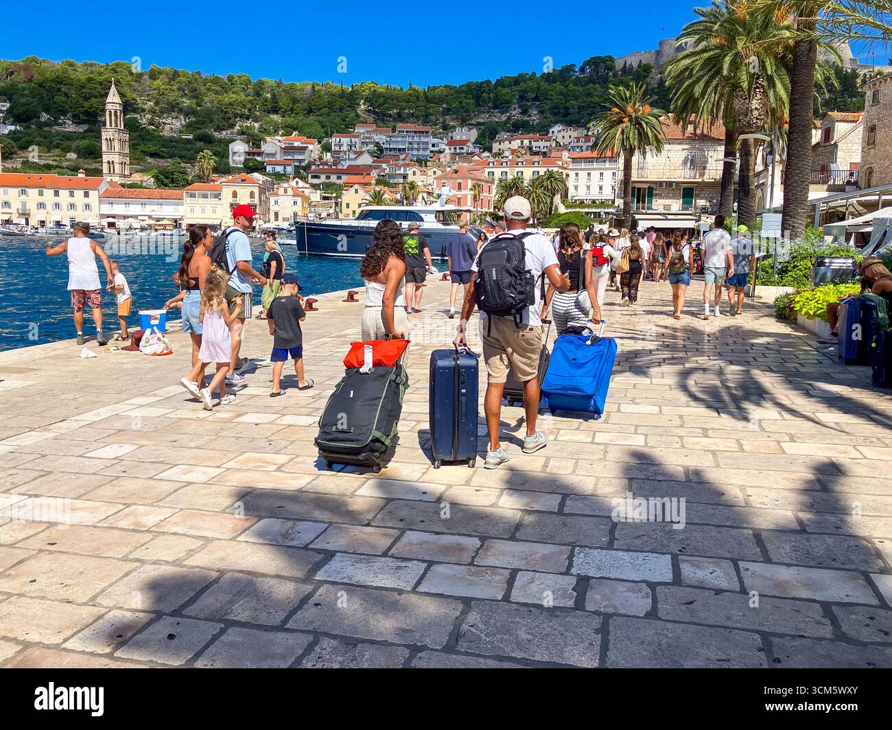 Città di Hvar e gemma croata. Turisti che arrivano dal traghetto nell'antica città con strade acciottolate, architettura veneziana e acque cristalline. Foto Stock