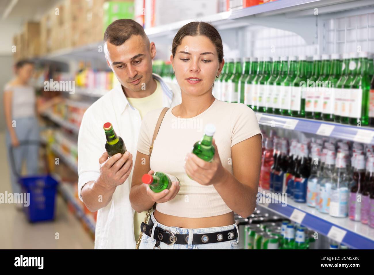 Giovane coppia amichevole che sceglie bevande alcoliche nel supermercato Foto Stock