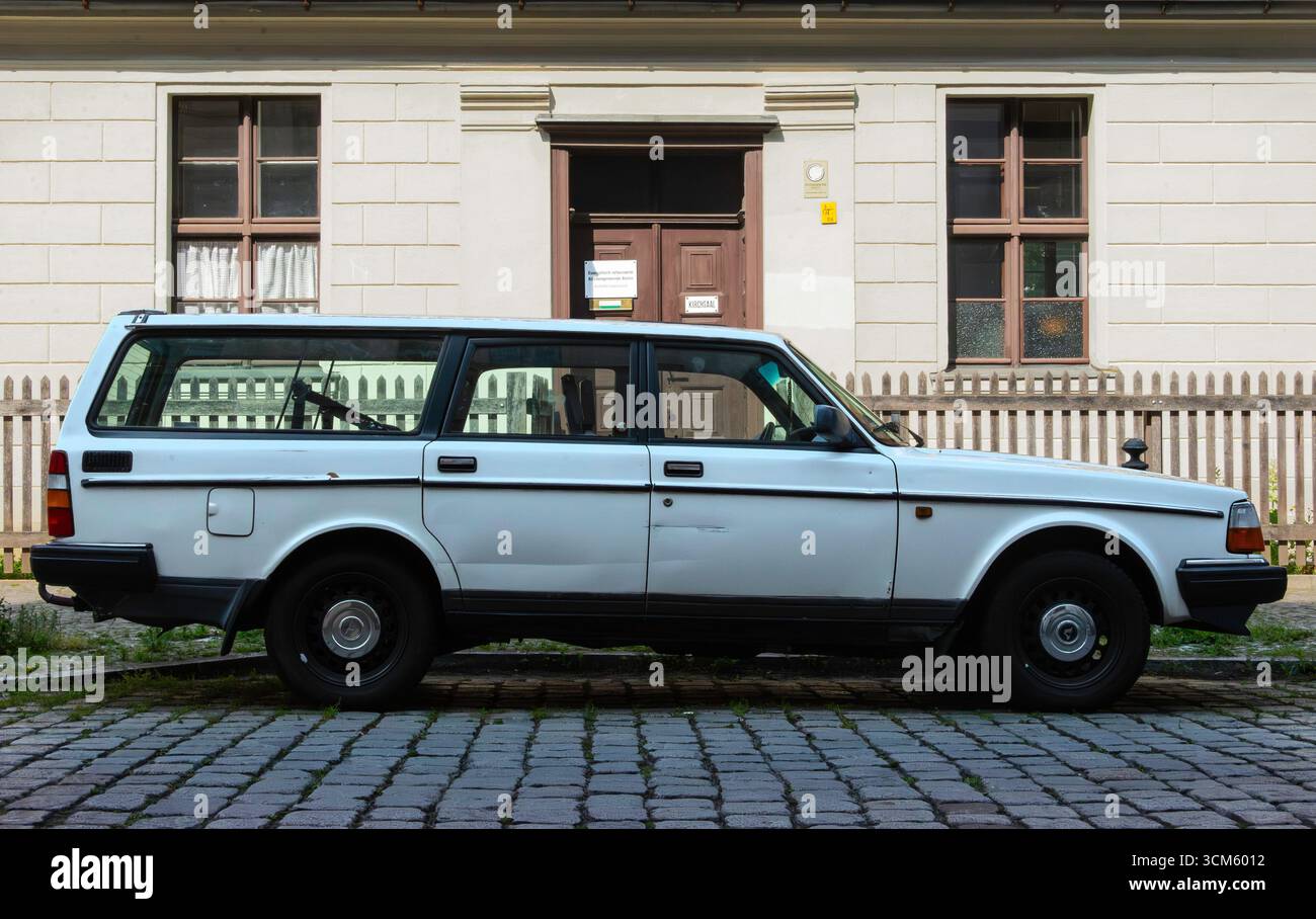 Una station wagon Volvo 240 bianca d'epoca parcheggiata in una strada acciottolata nello storico quartiere Rixdorf di Berlino, Germania. Una città europea senza tempo Foto Stock