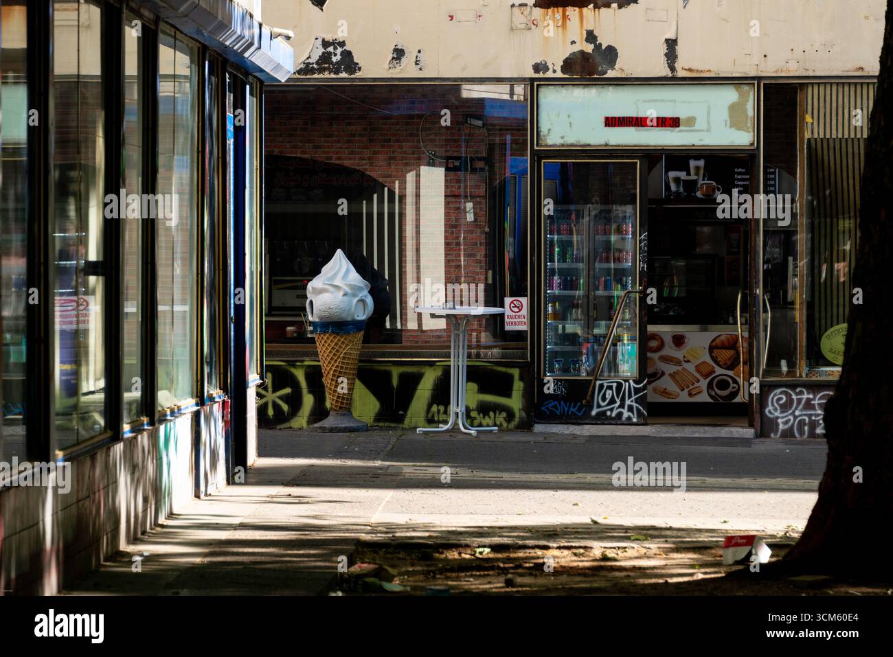 Un eccentrico cono per gelato su un marciapiede illuminato dal sole a Kreuzberg di Berlino. Il ripiano con graffiti e intemperie cattura un'autentica a Foto Stock