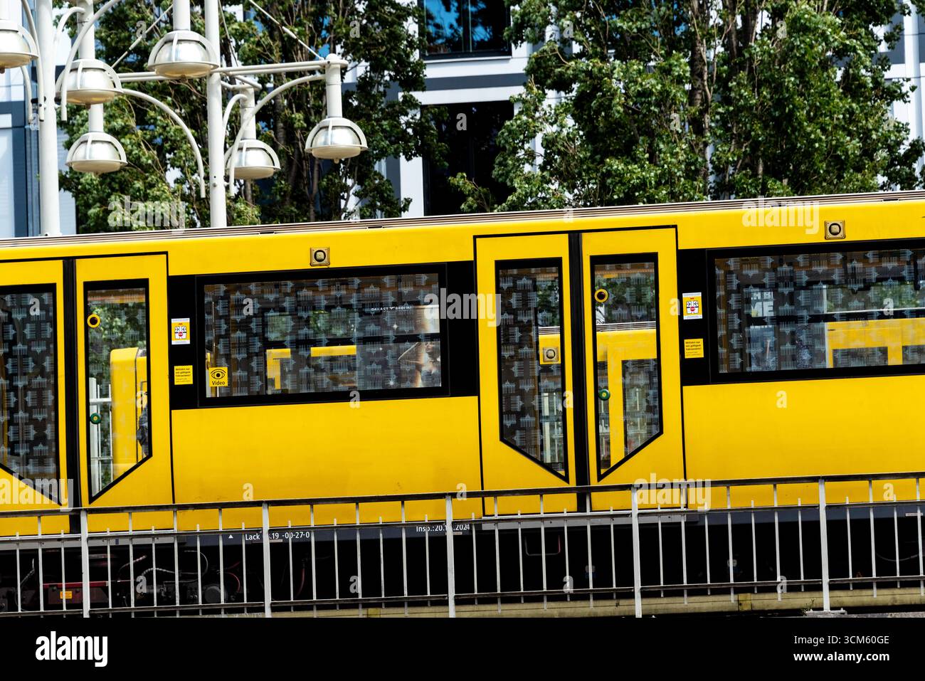 Un treno giallo vivace della U-Bahn di Berlino alla stazione Warschauer Straße. La vista laterale dinamica cattura l'essenza dei trasporti pubblici urbani, della vita cittadina e del mese Foto Stock