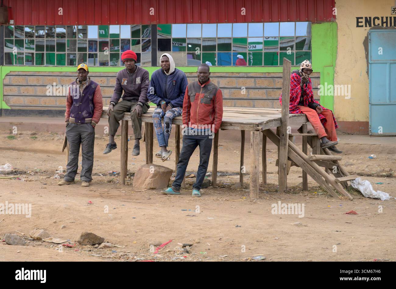 Uomini senza lavoro che si riuniscono la mattina a bordo strada nella speranza di ottenere un incarico temporaneo, nella contea di Narok, Kenya. Foto Stock
