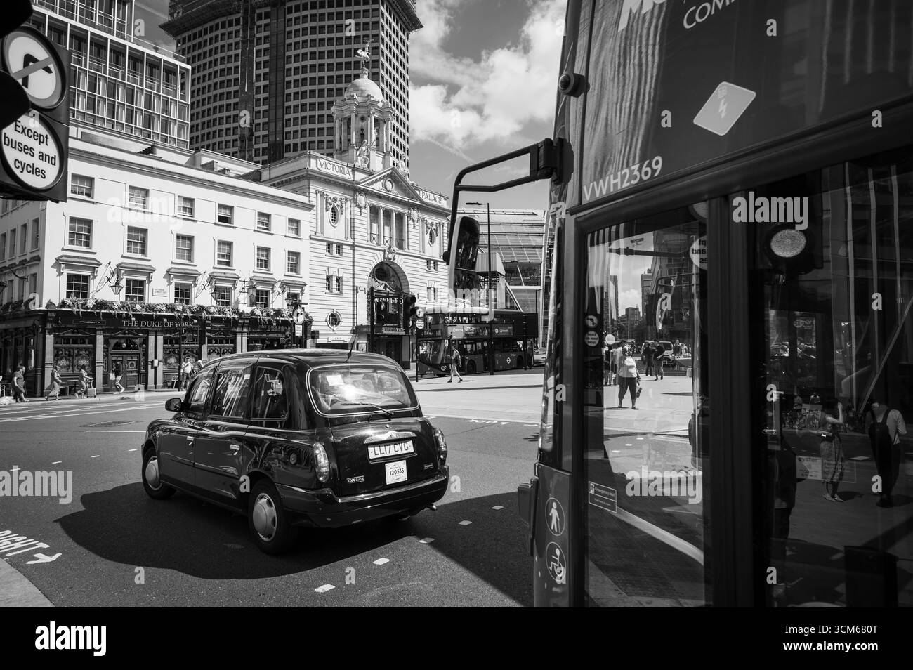 Autobus a due piani di Londra e taxi neri di fronte alla storica Victoria Station di Londra. Londra, Regno Unito. Immagine in bianco e nero. Foto Stock