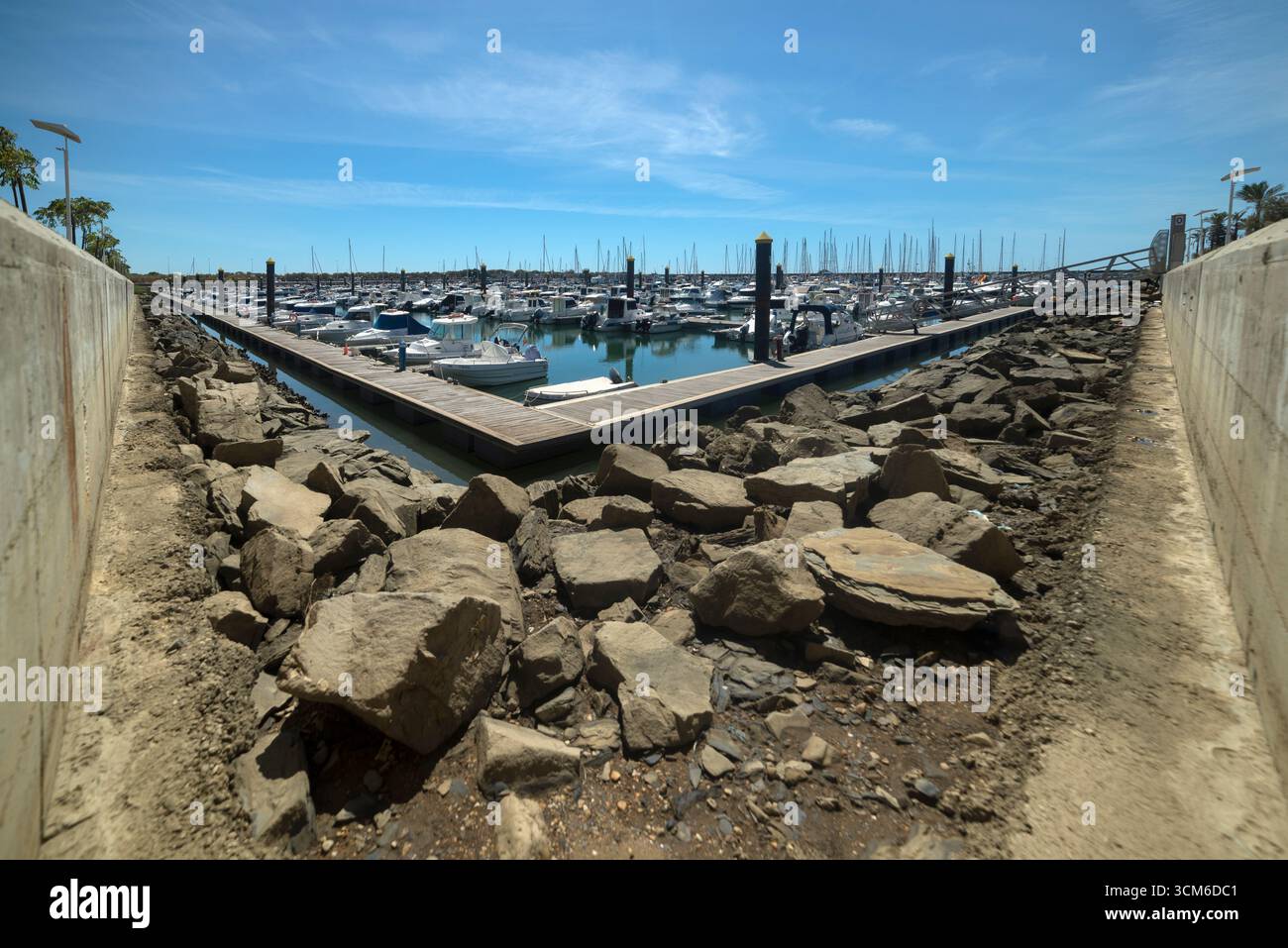 Porticciolo di Mazagón, con barche di varie dimensioni ormeggiate in una giornata di sole con acque calme e frangiflutti circostanti. Foto Stock