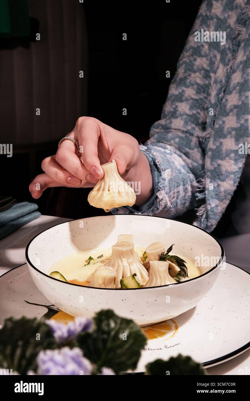 Gustosi bocconcini in un brodo cremoso che delizia e sono gustati da una mano di Diners Foto Stock