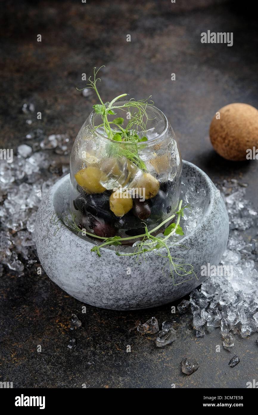 Un'elegante e sorprendente presentazione di olive ed erbe fresche disposte ad arte sul ghiaccio Foto Stock