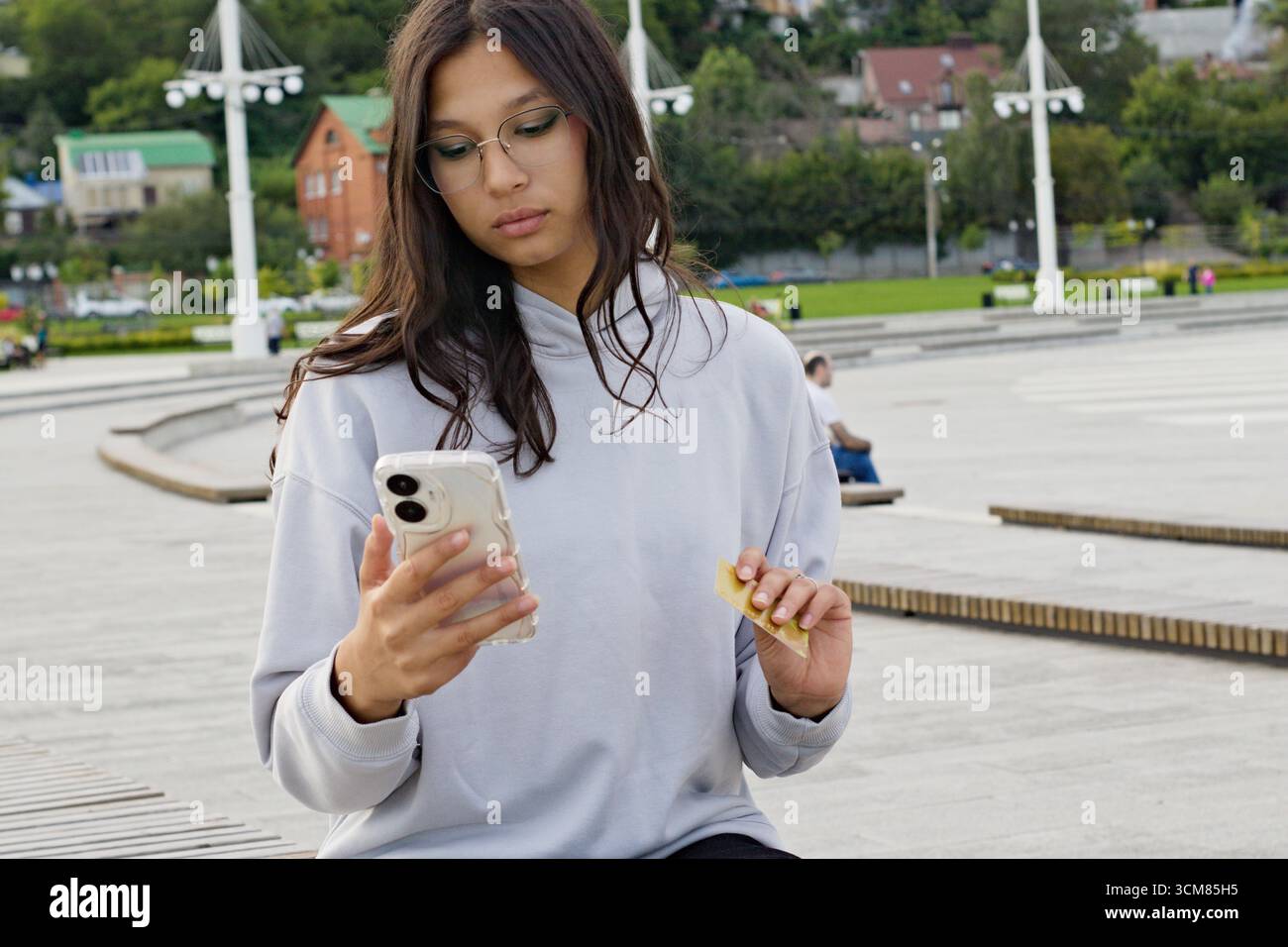 giovane donna in occhiali con carta di credito e telefono, studentessa universitaria Foto Stock