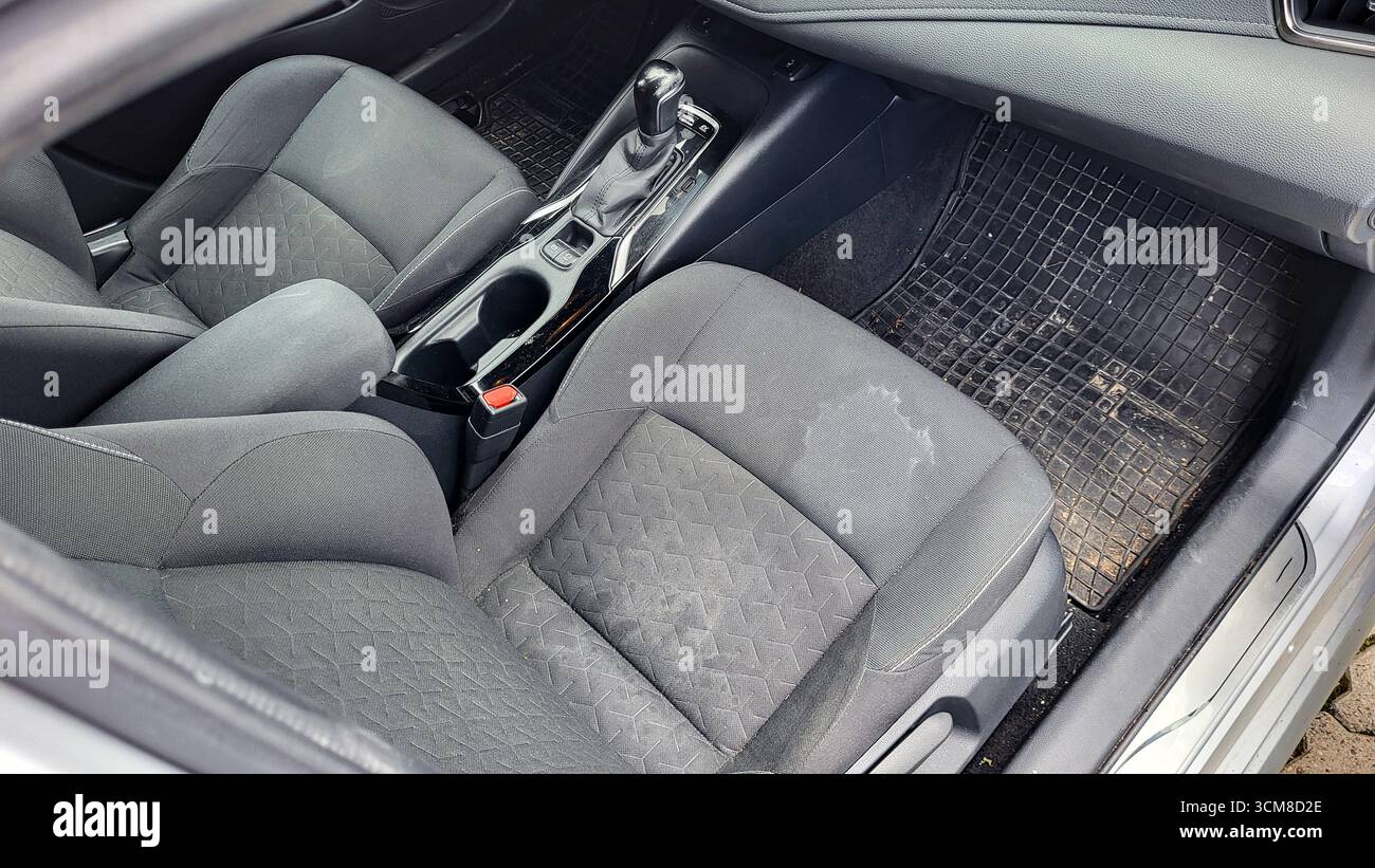 Abitacolo della vettura prima della pulizia. Interni sporchi in tessuto con macchie sui sedili anteriori. Foto Stock