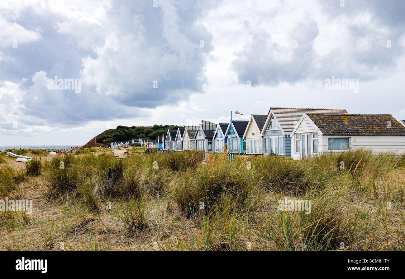 Le famose e colorate capanne sulla spiaggia e le case vacanza di Hengistbury Head si affacciano sul porto di Christchurch e sul mare vicino a Bournemouth UK Foto Stock