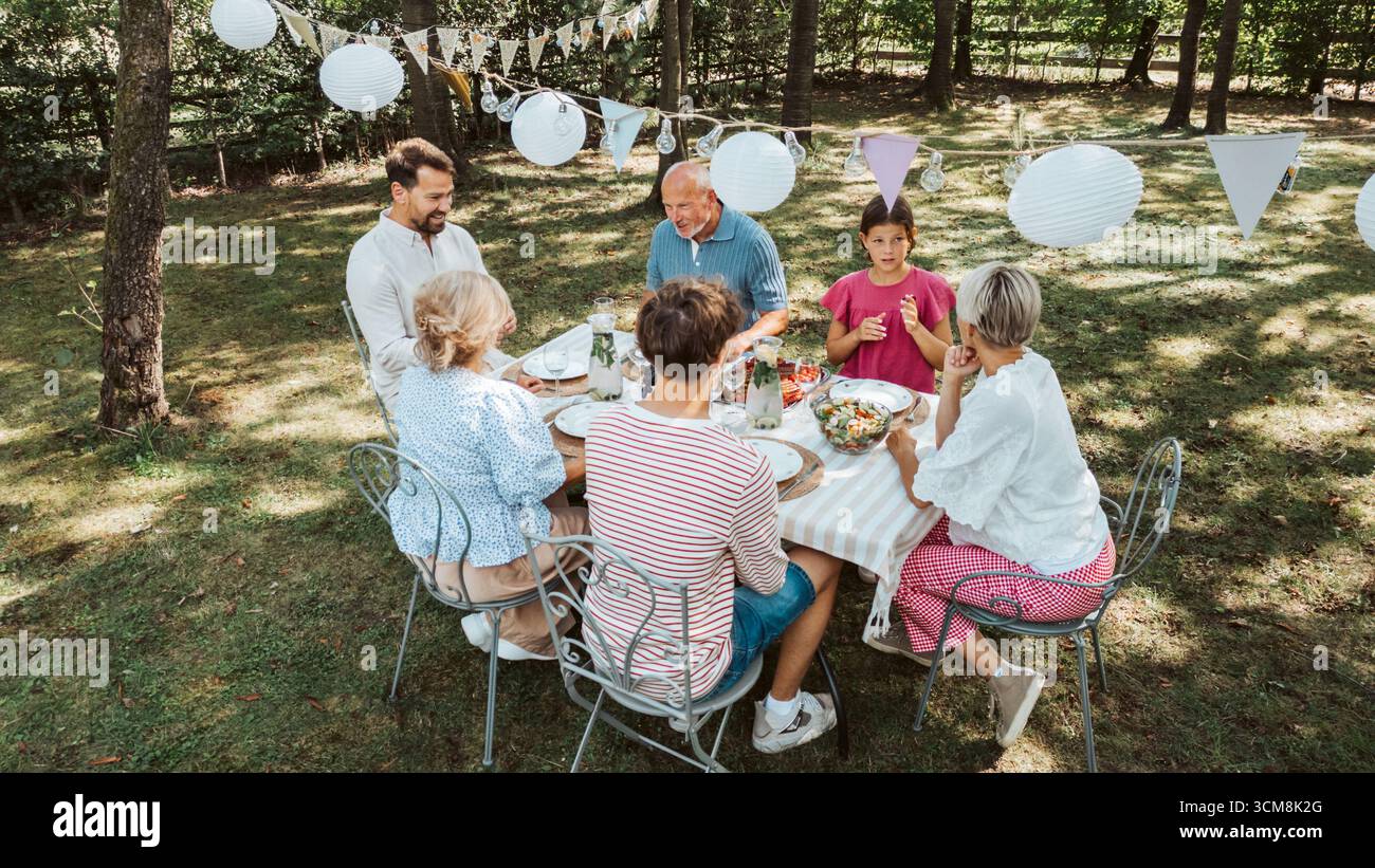 Vista aerea dei nonni, dei genitori e dei bambini che cenano insieme all'esterno, festa alla griglia nel fine settimana. Foto Stock