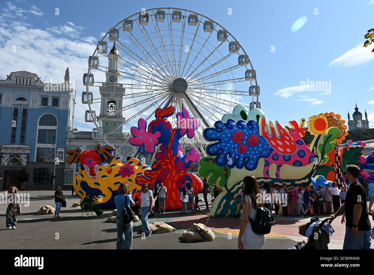 I residenti di Kiev e gli ospiti della capitale camminano lungo Piazza Kontraktova sullo sfondo della ruota panoramica e l'installazione di sculture gonfiabili del duo artistico newyorkese "Chiaozza" (Adam Frezza e Terri Chiaode) ispirate al lavoro dell'artista Ucraina Maria Prymachenko, nel mezzo dell'invasione russa dell'Ucraina. L'Ucraina continua a difendersi dall'aggressione militare russa per il quarto anno dopo l'invasione del 24 febbraio 2022, con bombardamenti del territorio ucraino che continuano quotidianamente. (Foto di Aleksandr Gusev/SOPA Images/Sipa USA) Foto Stock