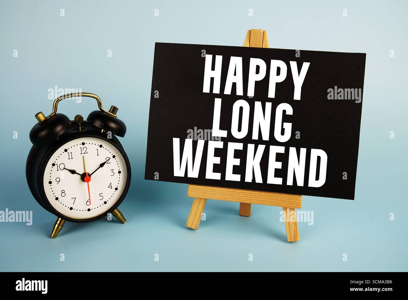 Testo del weekend lungo e felice con cavalletto e sveglia su sfondo blu Foto Stock