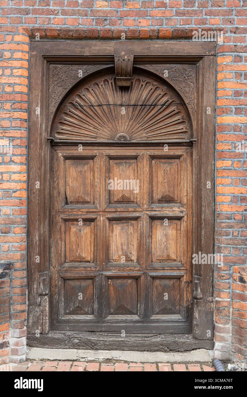 Primo piano di una porta in legno con un design solare in cima al George Abbot Hospital, Guildford, Surrey, Inghilterra, Regno Unito Foto Stock