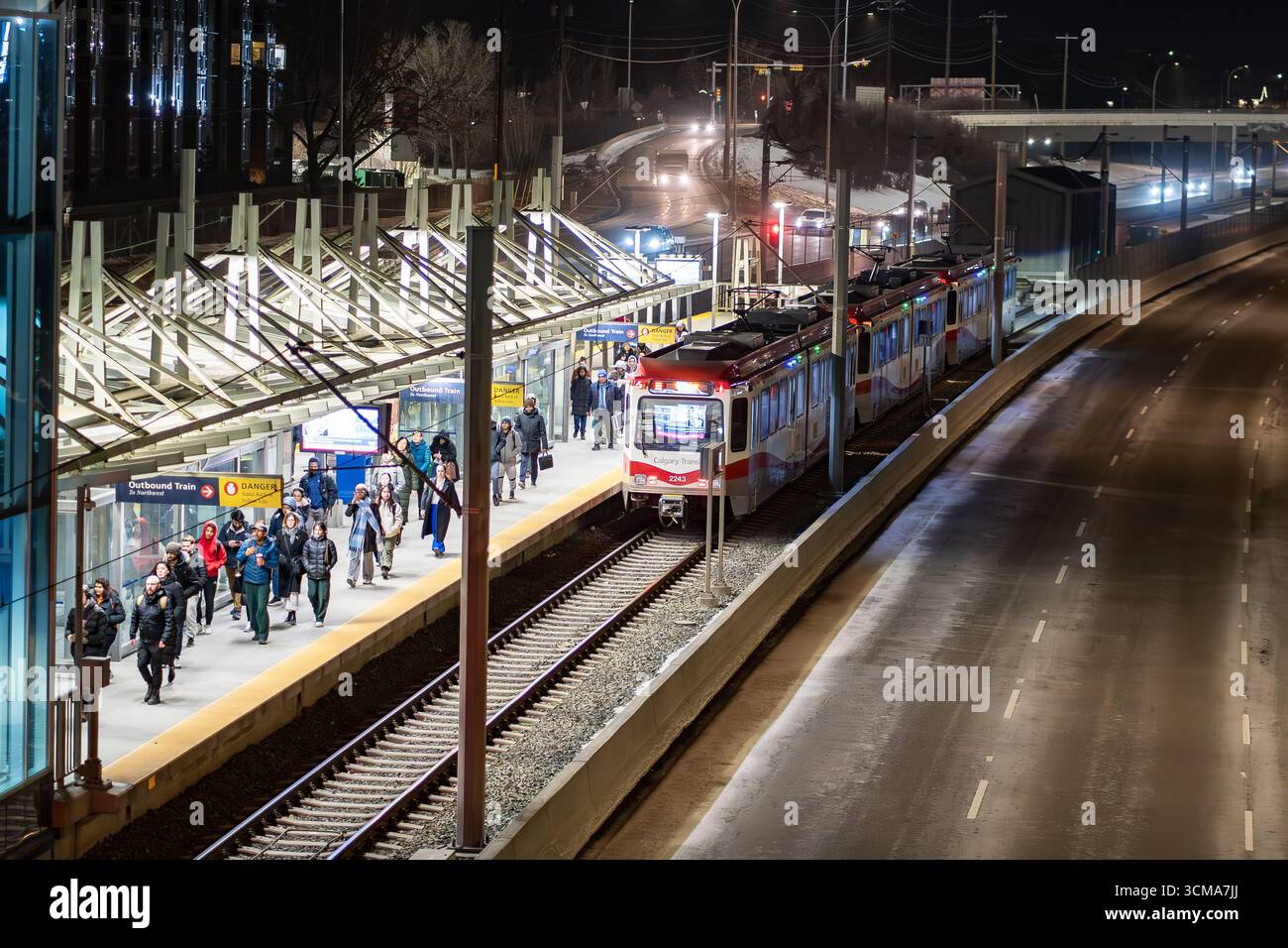 Calgary, Alberta Canada, 20 aprile 2025: I pendolari lasciano un treno leggero che cammina lungo una piattaforma in prima serata. Foto Stock