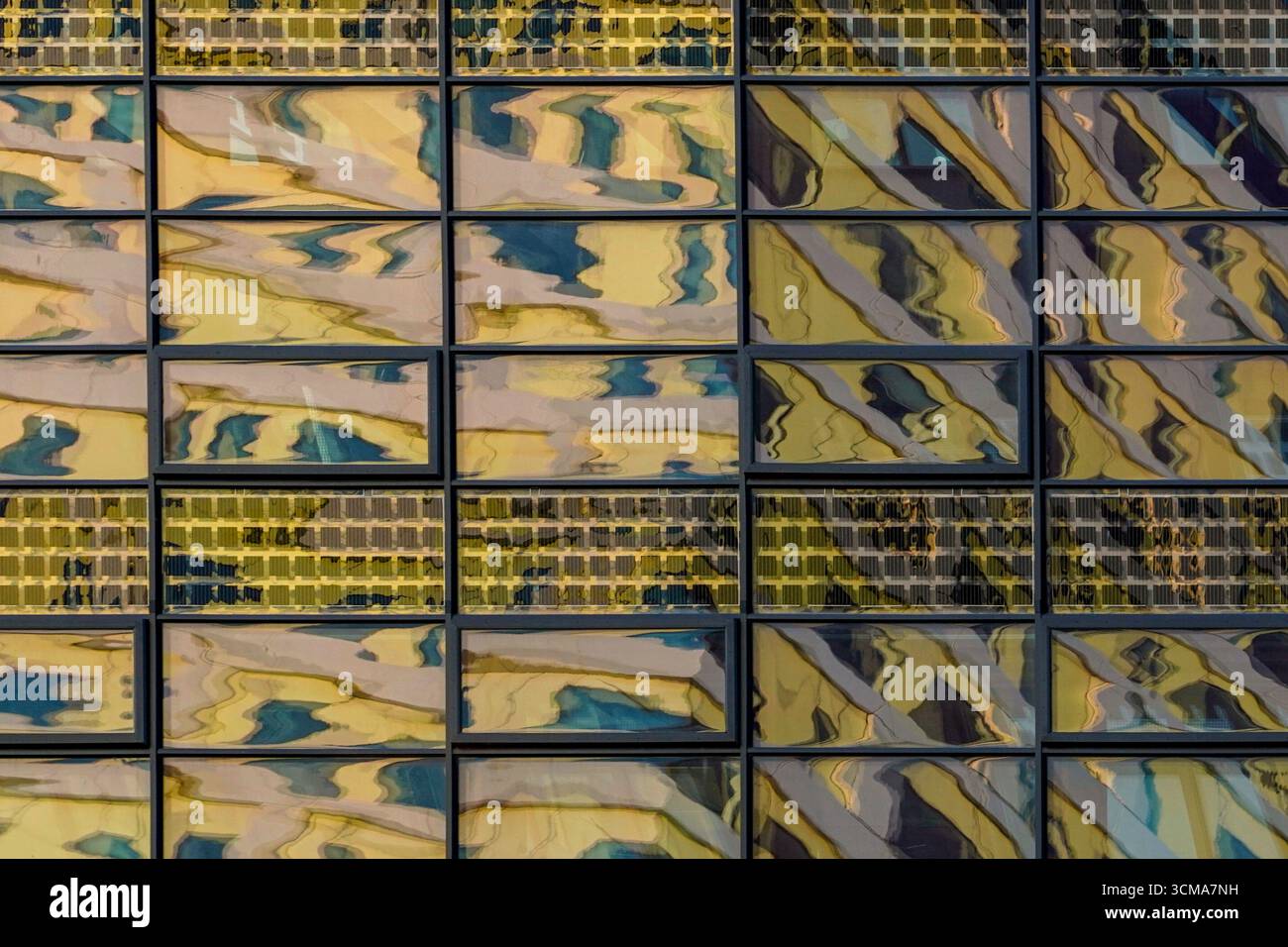 Malmö, Svezia. Una facciata in vetro di un edificio per uffici riflette paesaggi urbani distorti in schemi frammentati di luce e ombra. Foto Stock