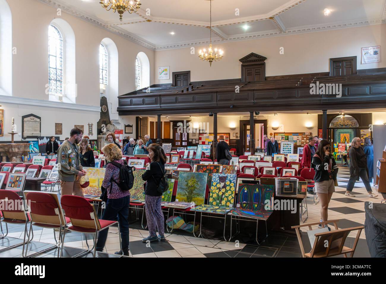 Persone che guardano alla mostra d'arte nella Holy Trinity Church nel centro di Guildford, Surrey, Inghilterra, Regno Unito Foto Stock