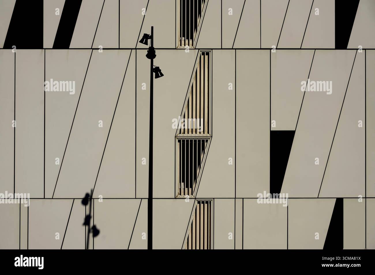 Gioco geometrico: Facciata dinamica. L'AC Hotel bella Sky a Copenhagen, Danimarca, progettato da 3XN Architects, presenta una facciata di pannelli bianchi segmentati con finestre scure, dove un'ombra di lampione esalta il ritmo geometrico. Foto Stock